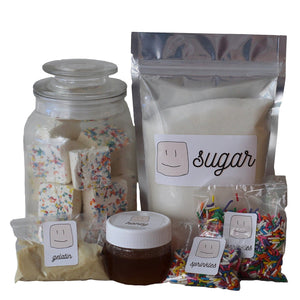 ingredients in the marshmallow making kit, bag of sugar, jar of honey, packs of gelatin and sprinkles 