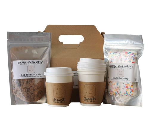 Display of items in the DIY hot chocolate kit. Includes one packet of hot chocolate mix, one package of marshmallows, gift box, and 4 small to-go cups