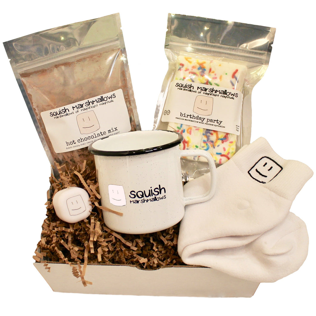 cozy kit includes logo mug, logo white socks, logo white lip balm, pack of hot chocolate mix, and pack of marshmallows